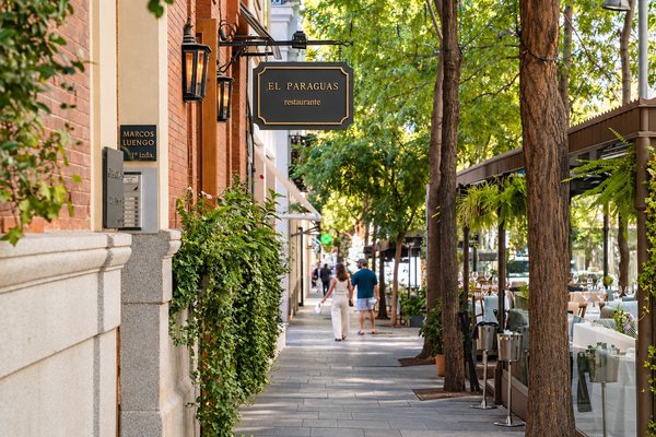 Acera arbolada con terrazas y portales del Barrio de Salamanca