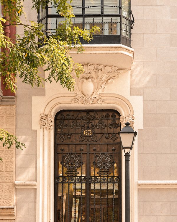 Portal de Casa Ayala con el número 63 en su reja de forja y decoración vegetal en piedra