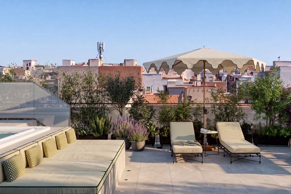 Terraza privada del ático dúplex con sofá corrido, sombrilla y tumbonas entre jardineras